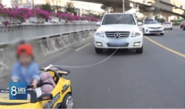 승용차에 어린이용 자동차를 연결해 도로에서 아이가 주행하는 모습이다.〈사진/SBS 뉴스〉
