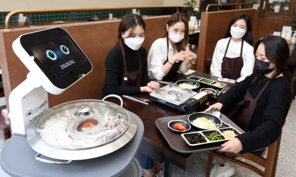음식점에서 사람 대신 로봇이 서빙하는 모습이다. 센서나 카메라가 있음에도 눈을 따로 표현했다.